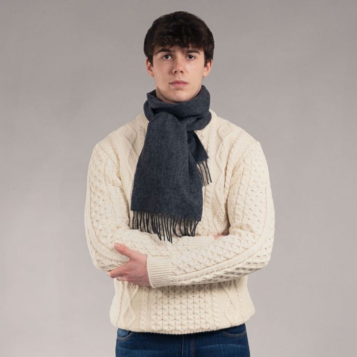Dark gray wool scarf with fringed edges, worn by a model.