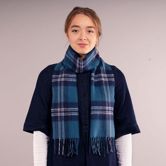 Teal and navy blue plaid wool scarf with white accents and fringed edges.