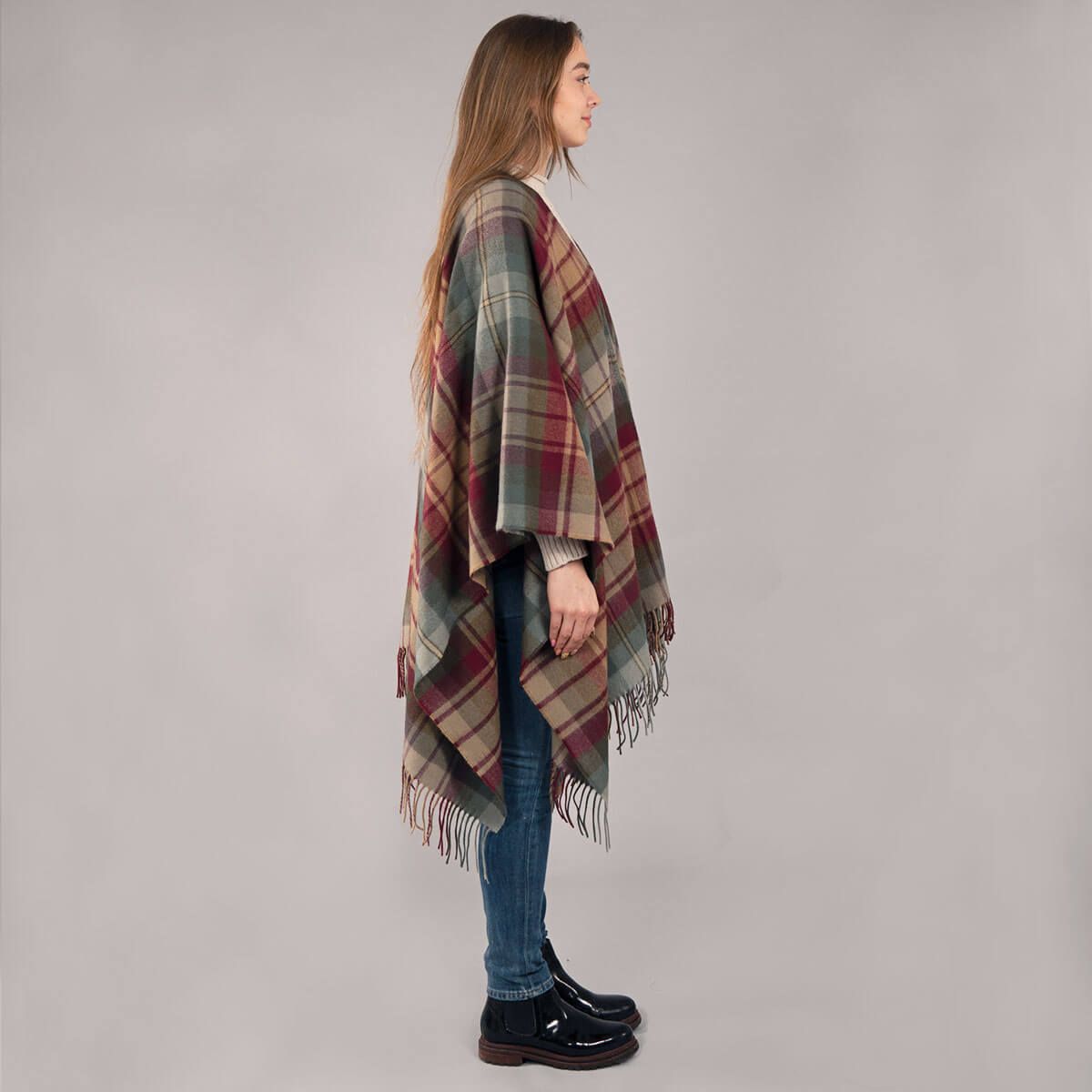 Woman wearing a plaid poncho on a plain background
