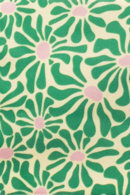 Fabric with a repeating pattern of stylized green flowers with pink centers on a pale yellow background.