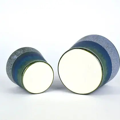 Pair of ceramic bowls, blue and green glazed, with off-white interiors.  Smaller bowl partially obscures larger bowl.