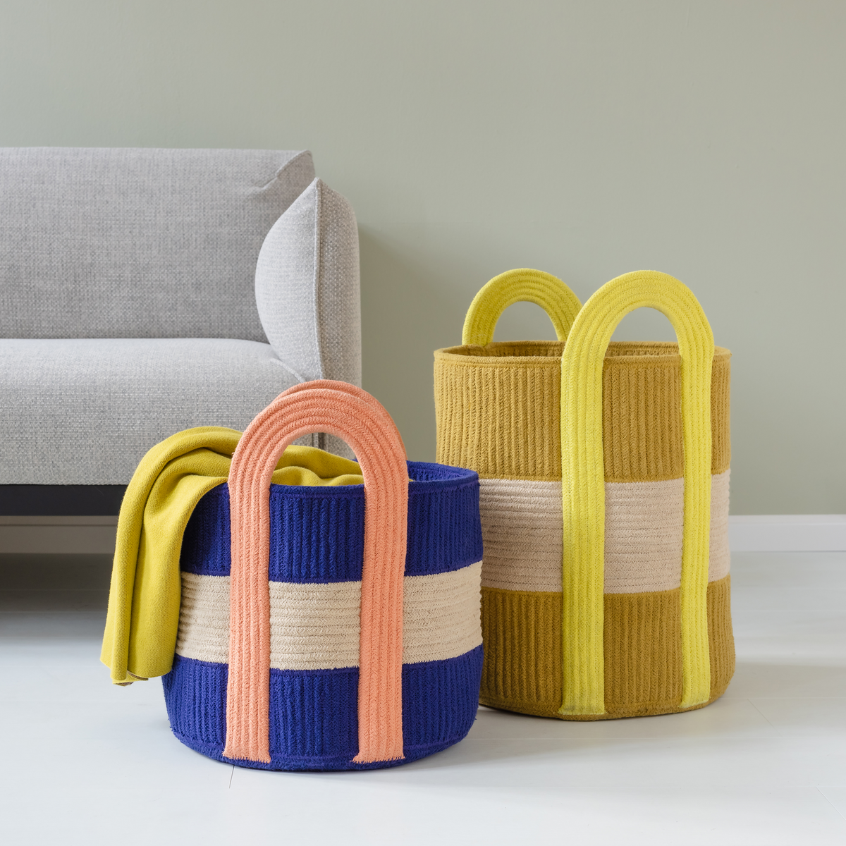 Colorful woven baskets with handles on a light surface.