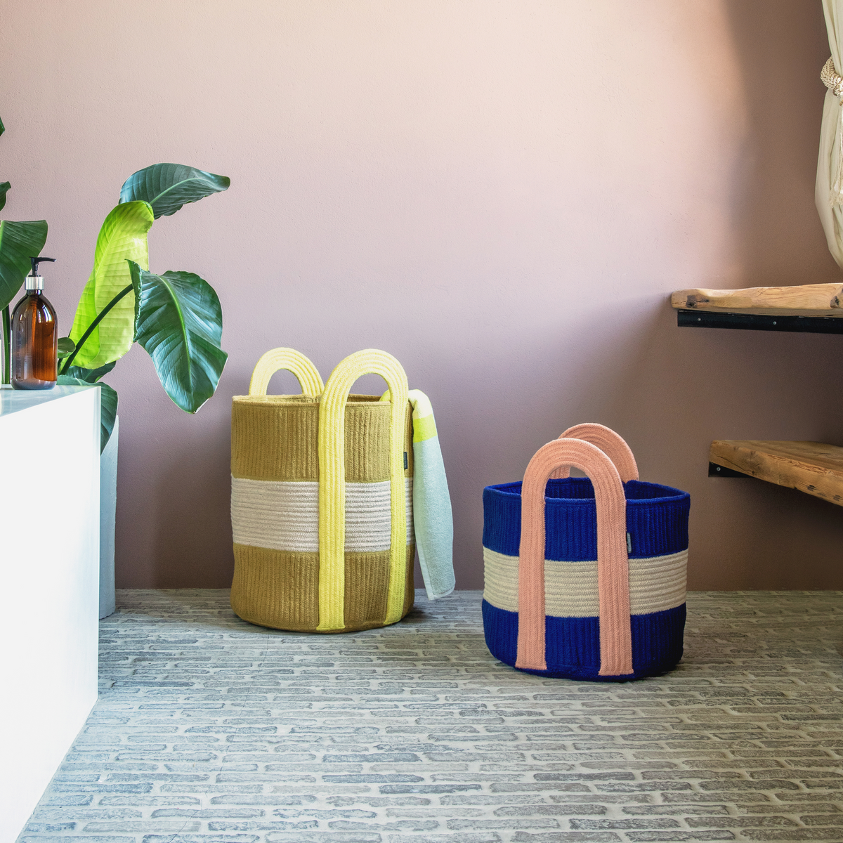Two woven baskets with colorful handles on a wooden floor.
