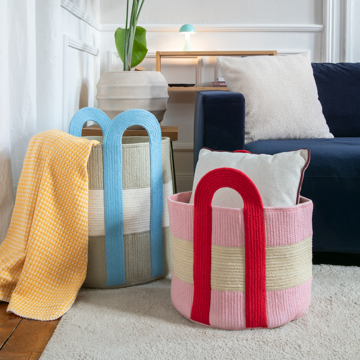Colorful woven baskets in a living room setting with a couch and pillows.
