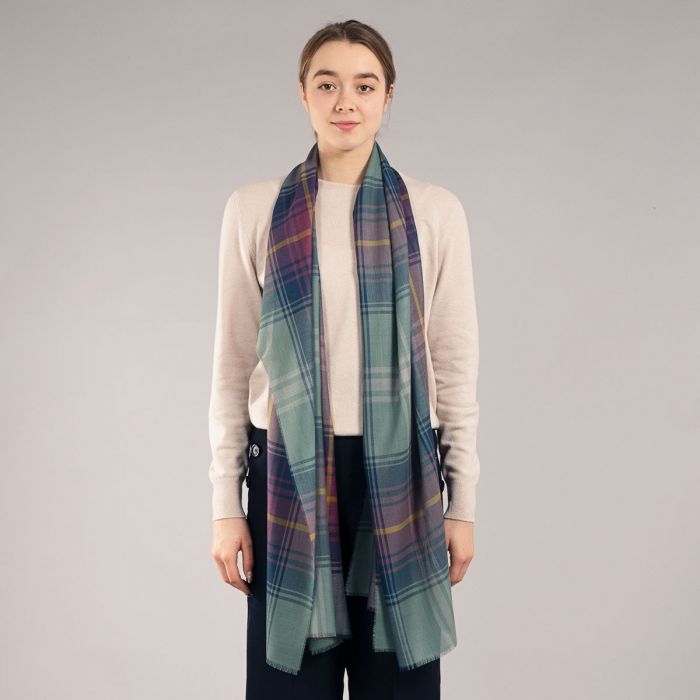 A sage green plaid scarf with purple and gold accents. The scarf is draped around a model's neck.