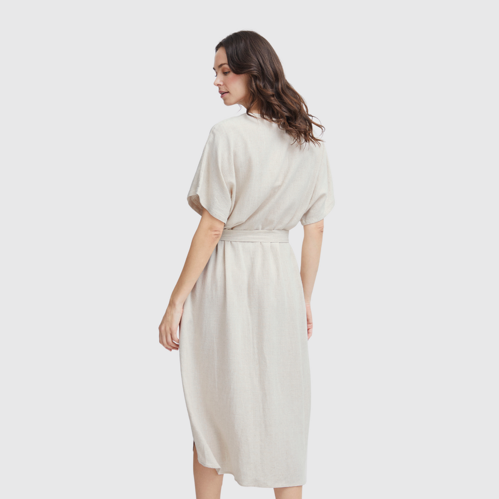 Woman in a beige Fransa dress, showing the back, with short sleeves and a belted waist.