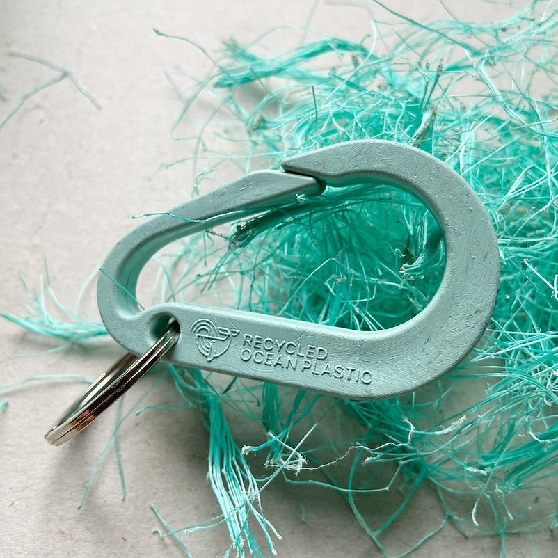 Light teal carabiner keychain made from recycled ocean plastic;  "Recycled Ocean Plastic" is embossed on the side.