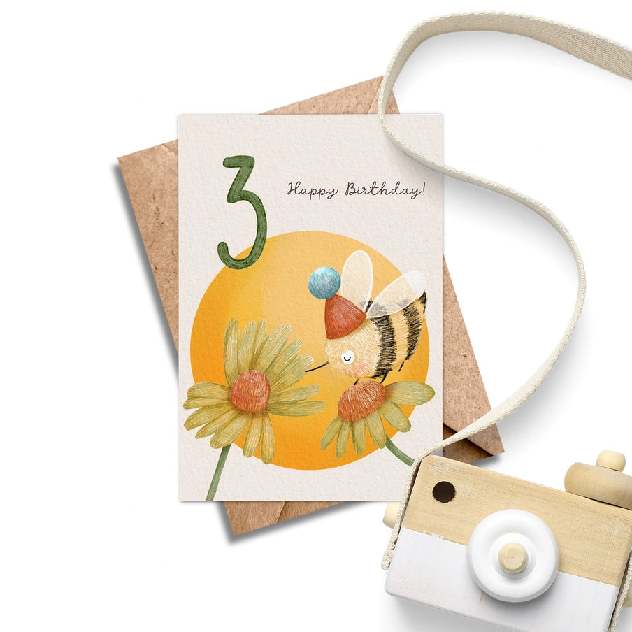 Third birthday card featuring a cartoon bee in a party hat near flowers; "Happy Birthday!" text.