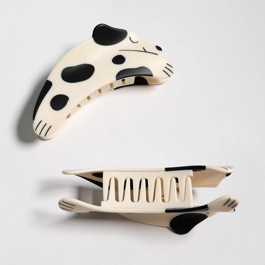 Two dog shaped hair clips with black spots on a light gray background