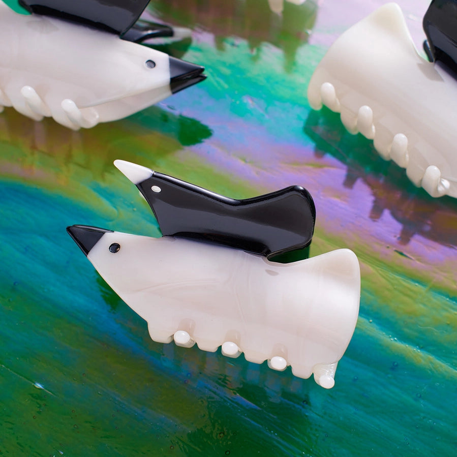 White and black bird shaped hair clips on a colorful surface