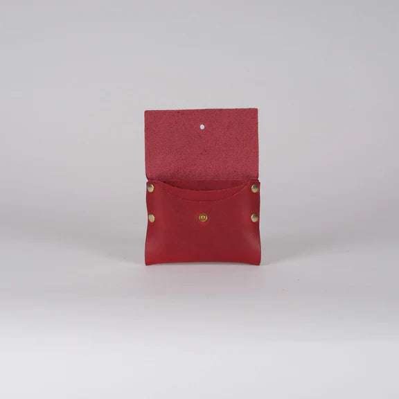 Red leather wallet with brass studs, open to reveal a small interior pocket and a snap closure.