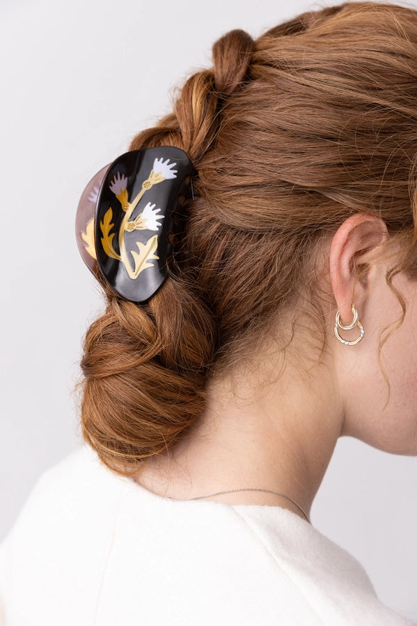 Person with braided hair wearing a decorative hair clip on a white background