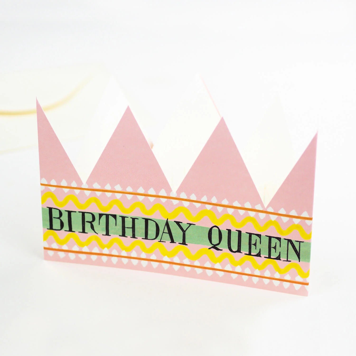 Pink paper crown with "Birthday Queen" in black lettering on a decorative band.
