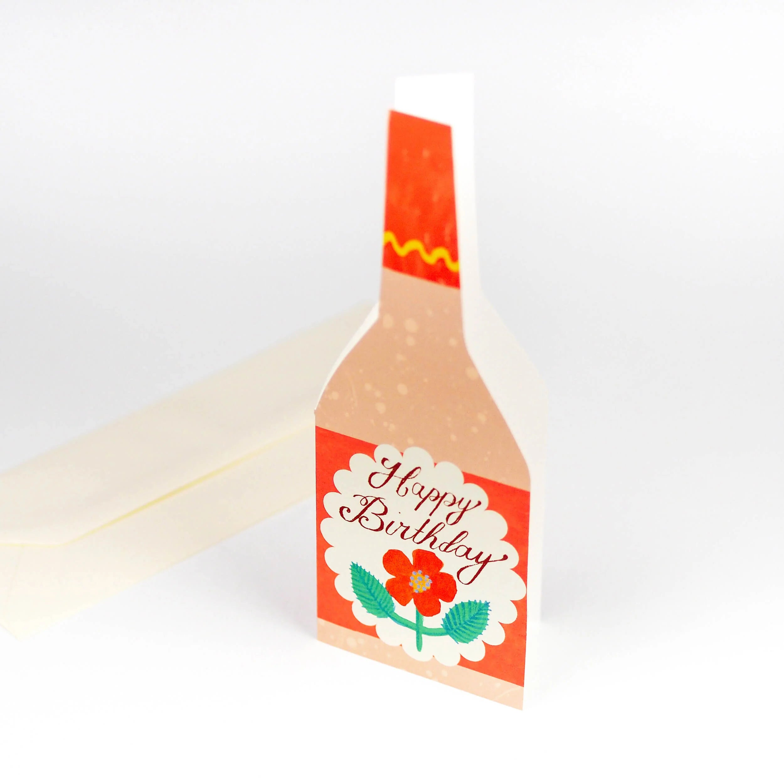 Happy Birthday card shaped like a bottle, featuring an orange design, a flower, and scalloped edges.
