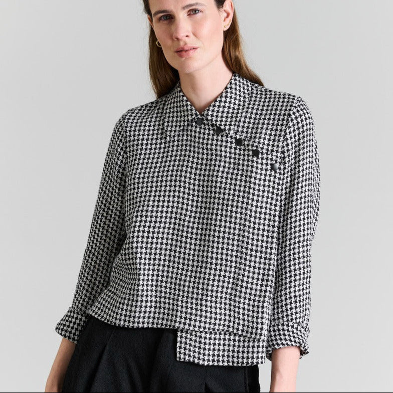 Woman wearing a black and white checkered shirt against a plain background