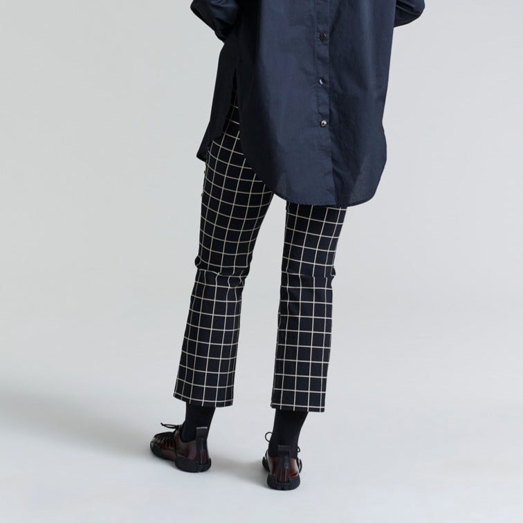 Person wearing a navy coat and black and white checkered pants on a light gray background