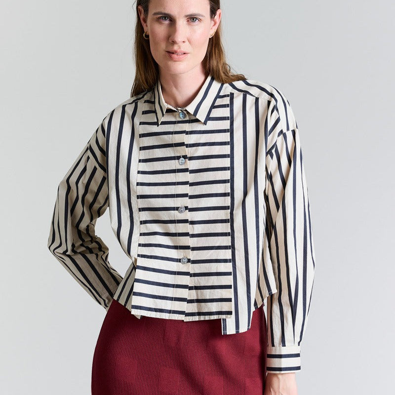 Woman wearing a striped shirt and red skirt against a plain background