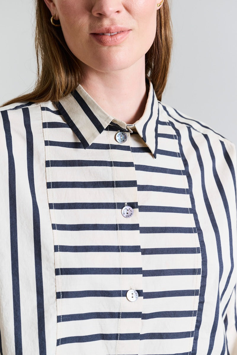 Close-up of a person wearing a striped shirt with a neutral background