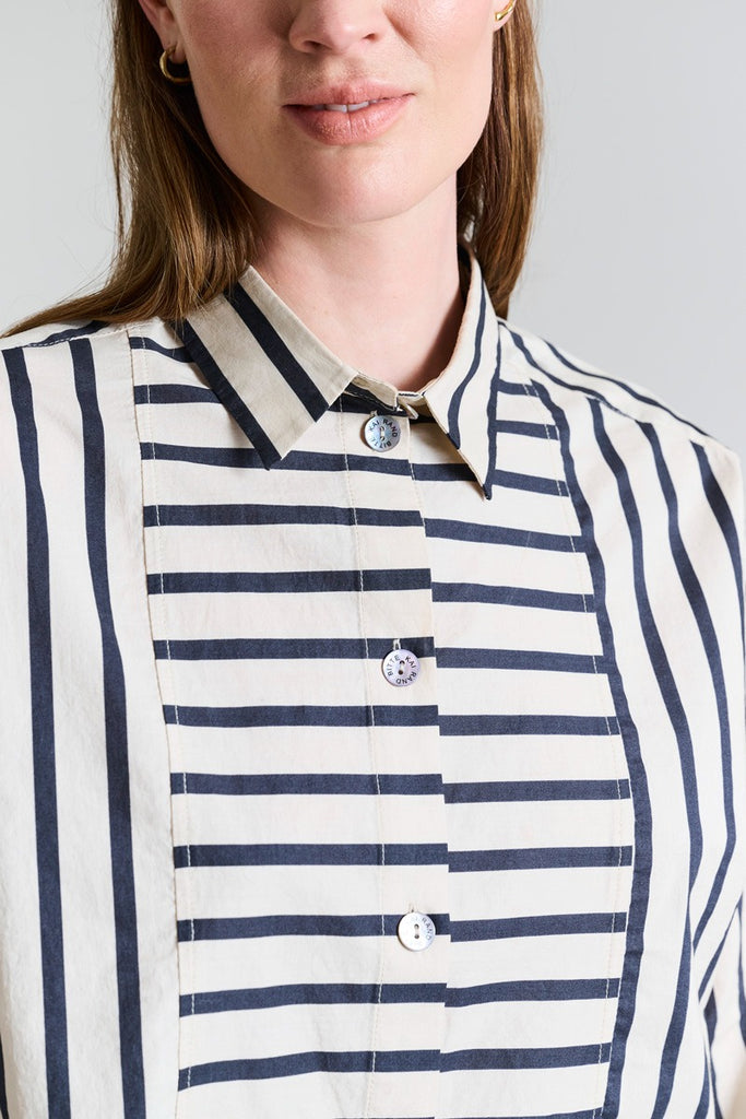 Close-up of a person wearing a striped shirt with a neutral background
