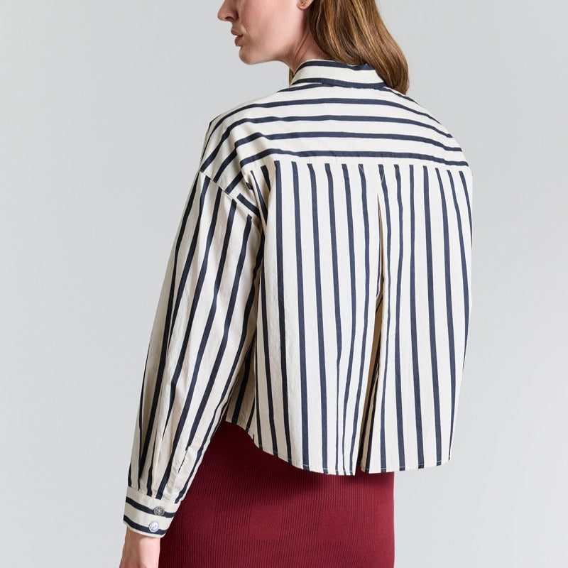 Woman wearing a black and white striped shirt against a plain background