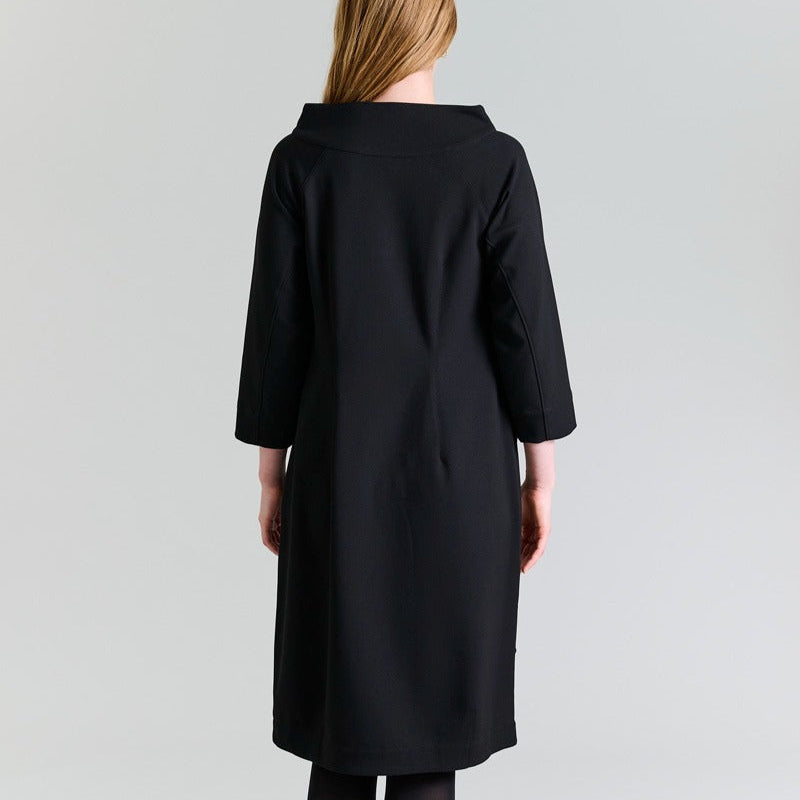 Person wearing a black coat on a gray background