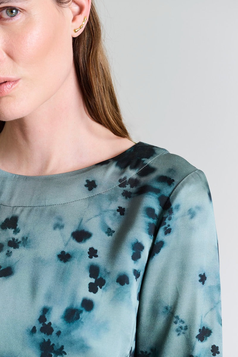 Woman wearing a blue floral blouse against a gray background