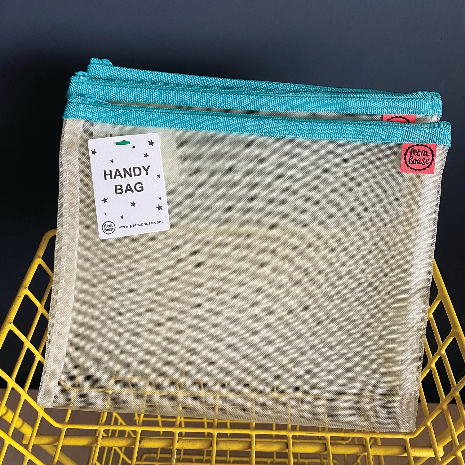 Cream-colored mesh storage bag with teal zipper, labeled "Handy Bag."