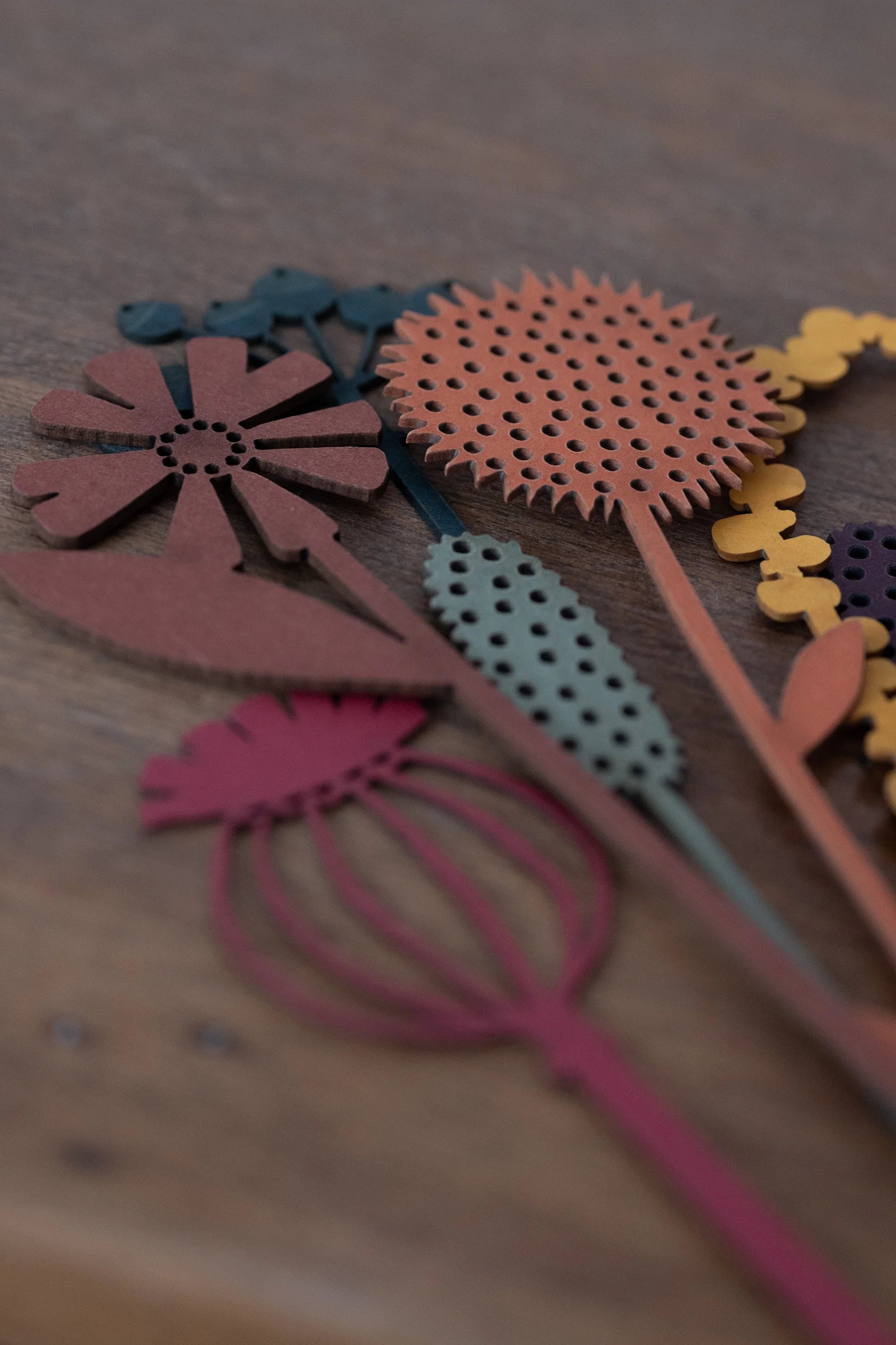 Collection of colorful, laser-cut flower shapes in various earthy tones.