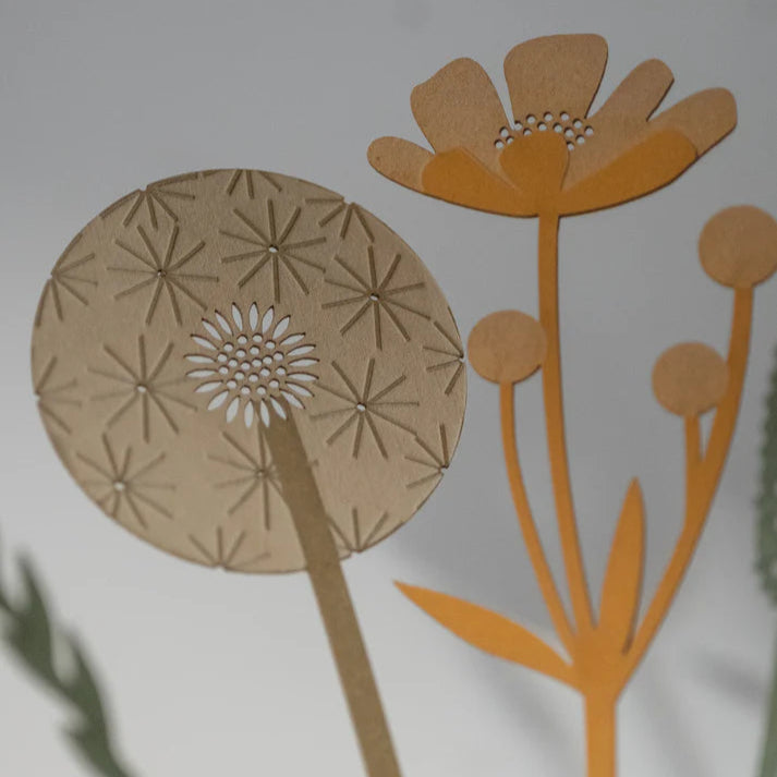 Intricate paper cut-out dandelion and flower design.