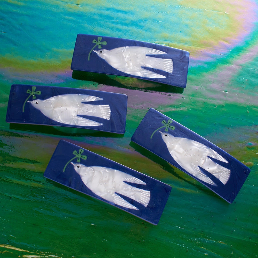 Four blue rectangular clasps with white dove designs on a colorful background