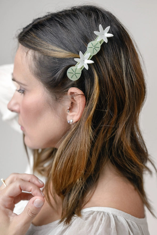 Woman with floral hair accessory and earrings against a neutral background