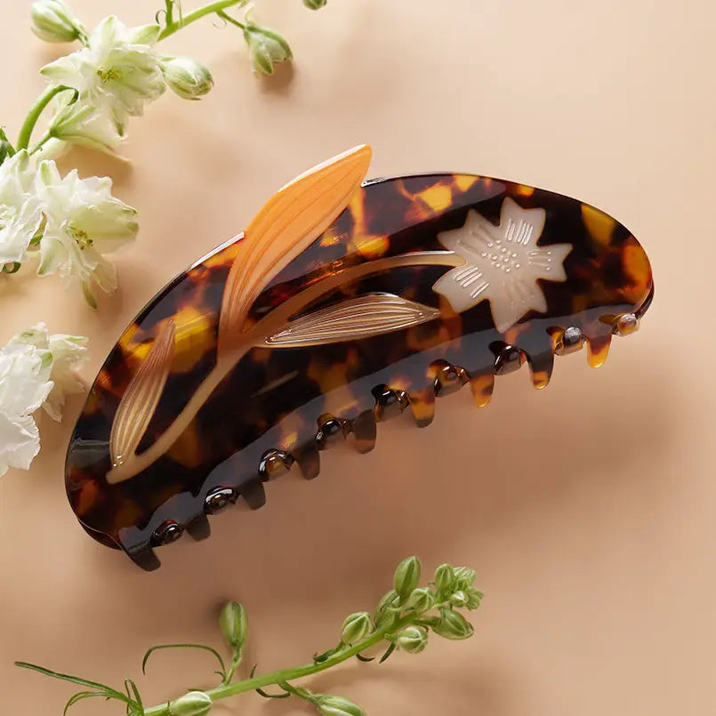 Tortoiseshell hair clip with floral design on a beige background