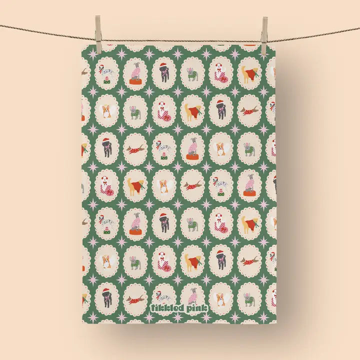 Christmas tea towel with repeating pattern of dogs in festive attire within decorative frames on a green background.