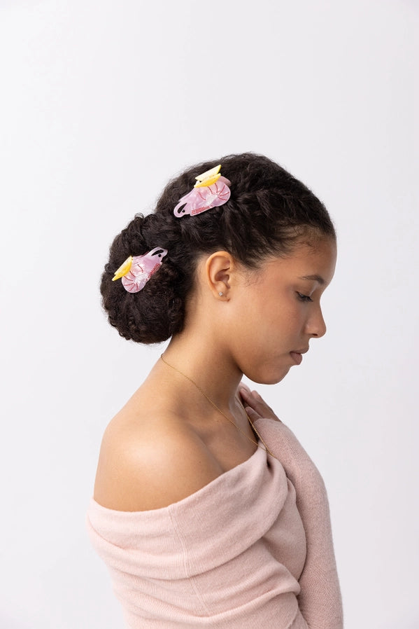 Woman with styled hair featuring pink prawn shaped hair accessories on a white background