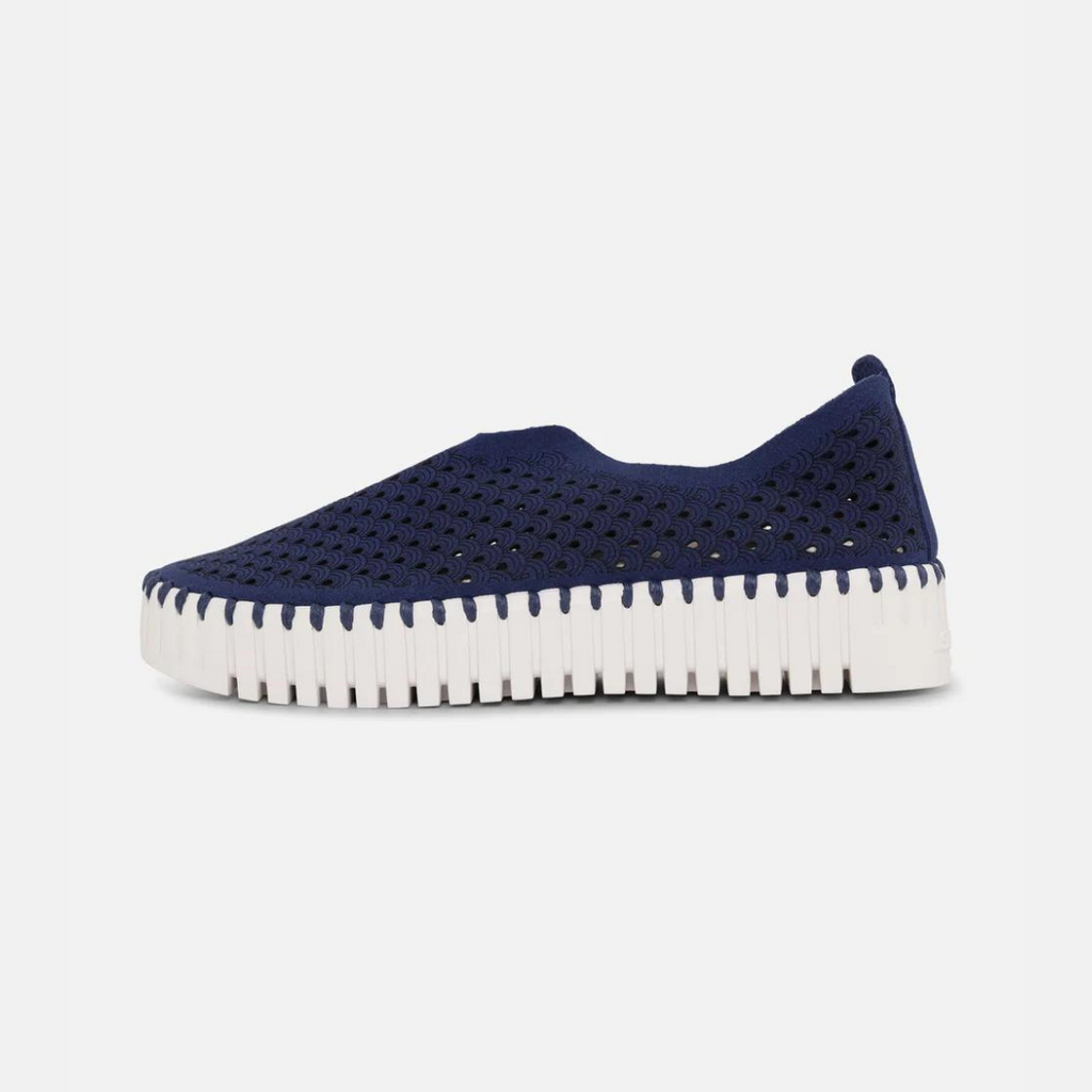 Navy blue slip-on sneaker with white textured sole and perforated upper.