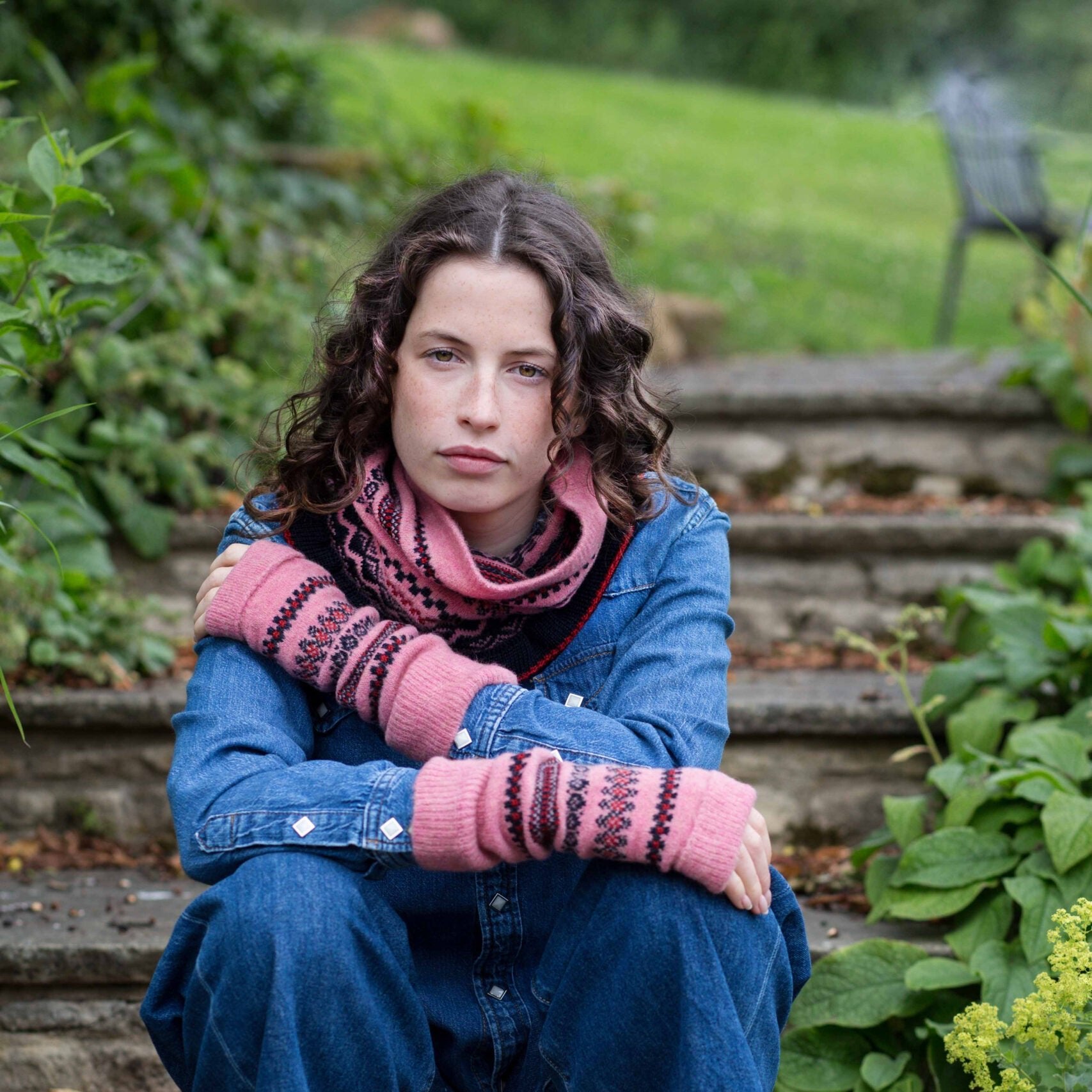 Pink knitted fingerless gloves and neck warmer with a Fair Isle pattern.