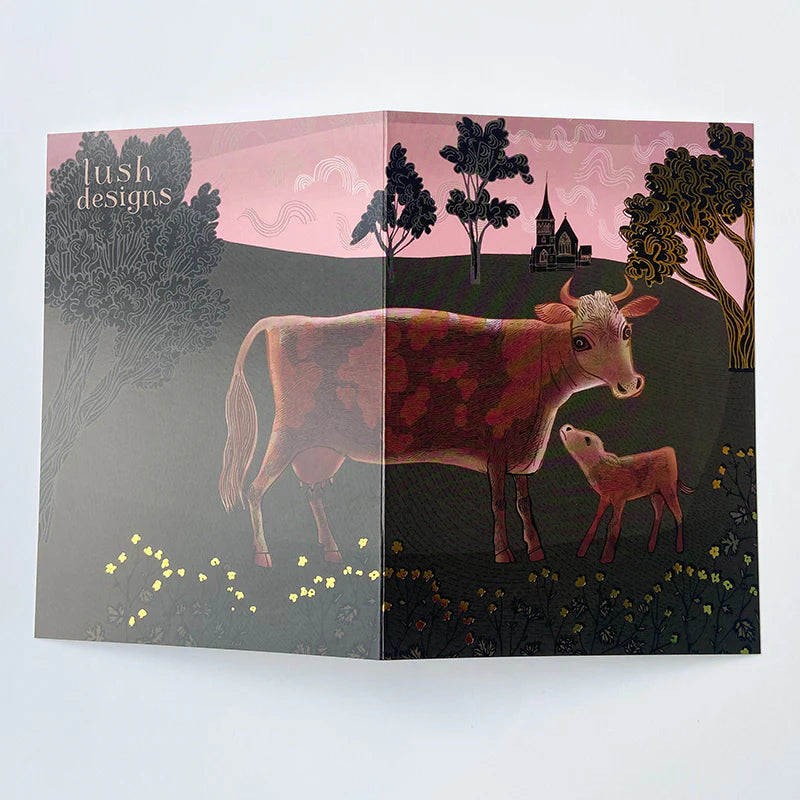 Card with illustration of a cow and calf in a pastoral scene, featuring 'lush designs' branding.