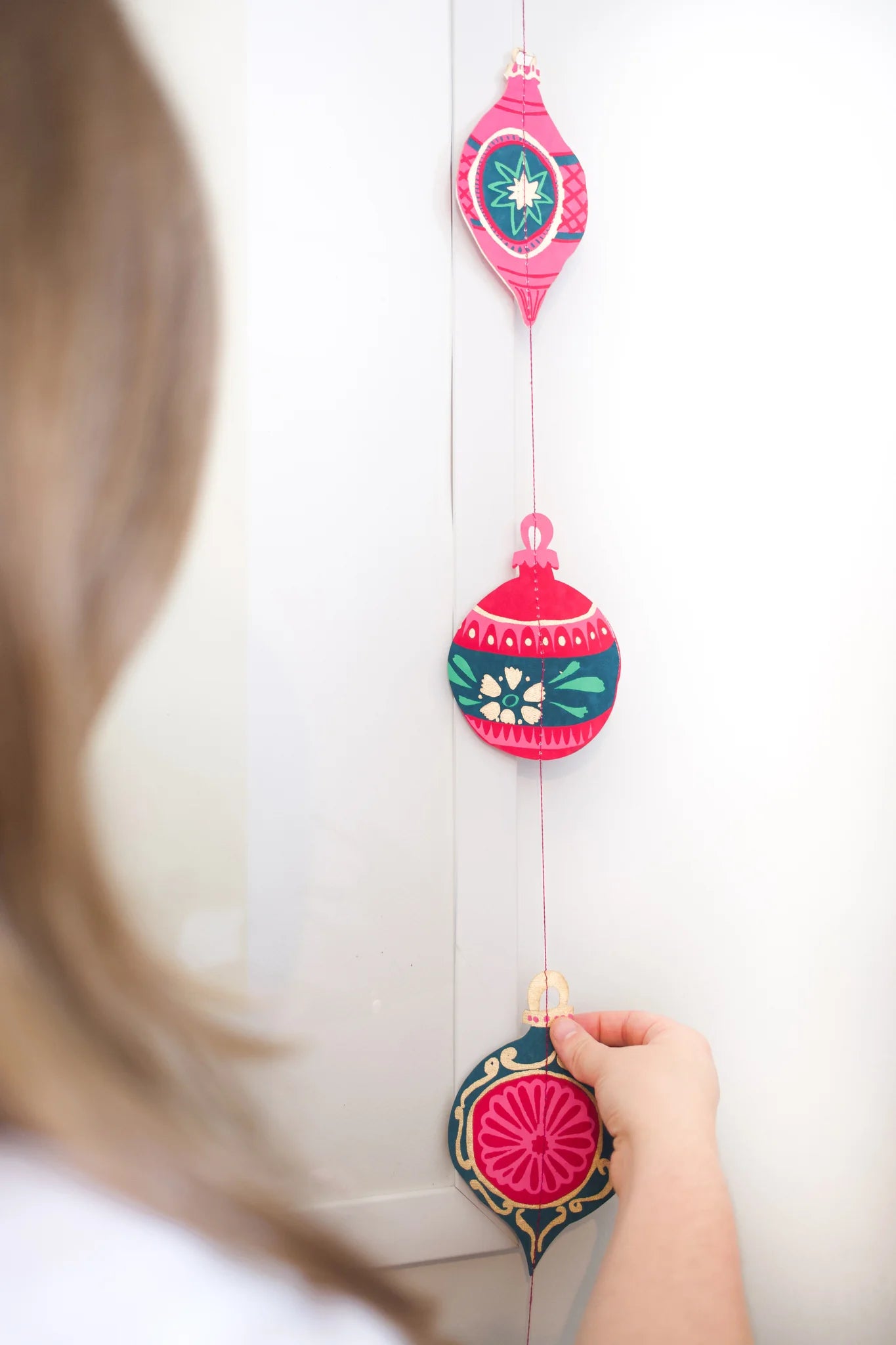 Decorative hanging ornaments with pink and blue designs on a white background