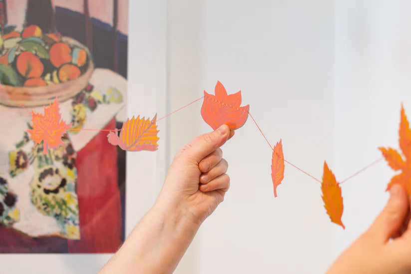 Autumn leaf garland with orange and peach colored leaves strung on thin thread.