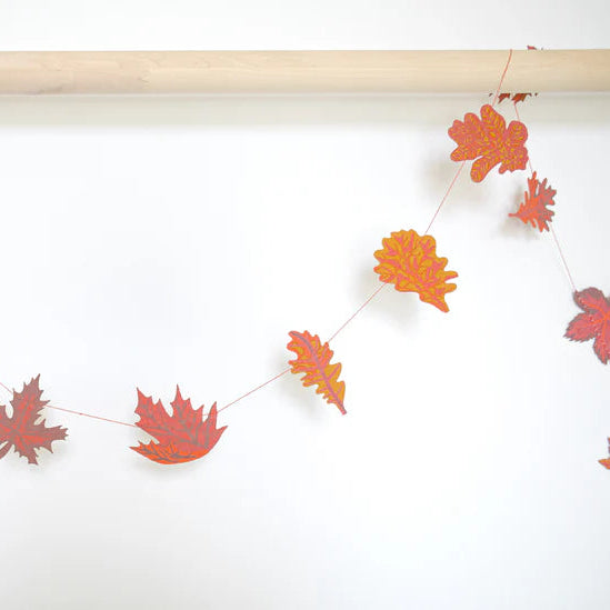 Autumn leaf garland with orange and red paper leaves of varying shapes strung on twine.