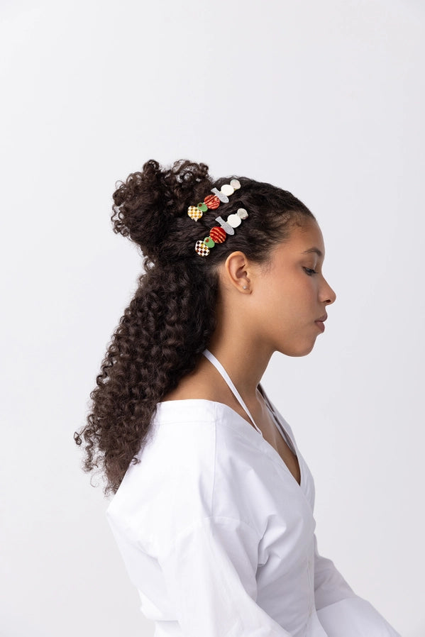 Woman with styled hair featuring colorful food themed hair accessories on a white background