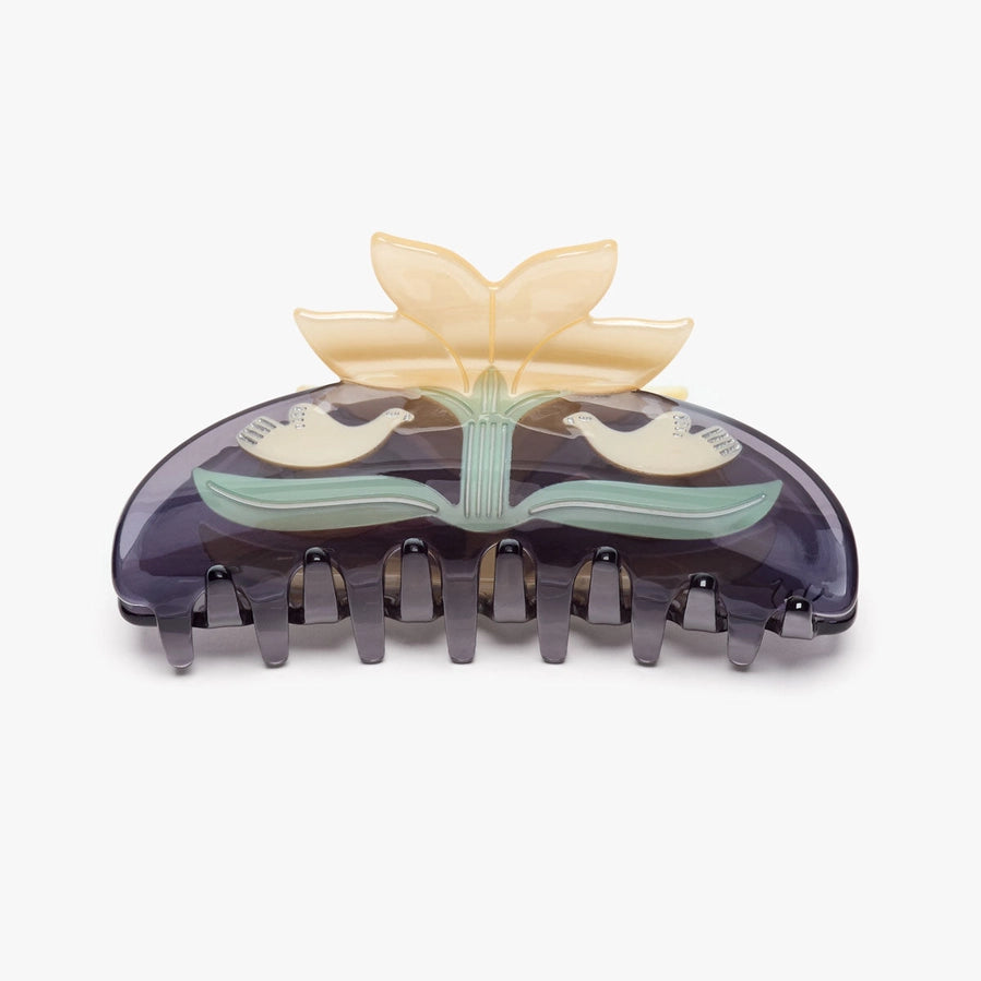 A translucent dark purple hair claw clip decorated with a light yellow lotus flower and green leaves, featuring two small white birds on the front, set against a plain light gray background.