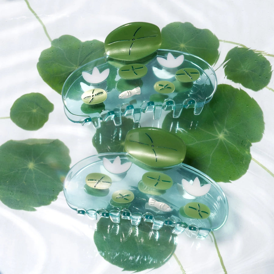 two clear hair clips with green lily pads and white flowers on a white background