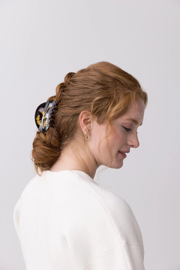 Woman with styled hair featuring a decorative hair clip against a plain background