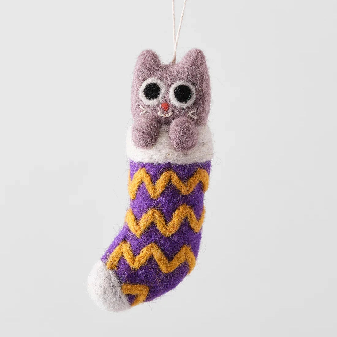 Needle-felted cat ornament inside a purple and gold chevron-patterned stocking.