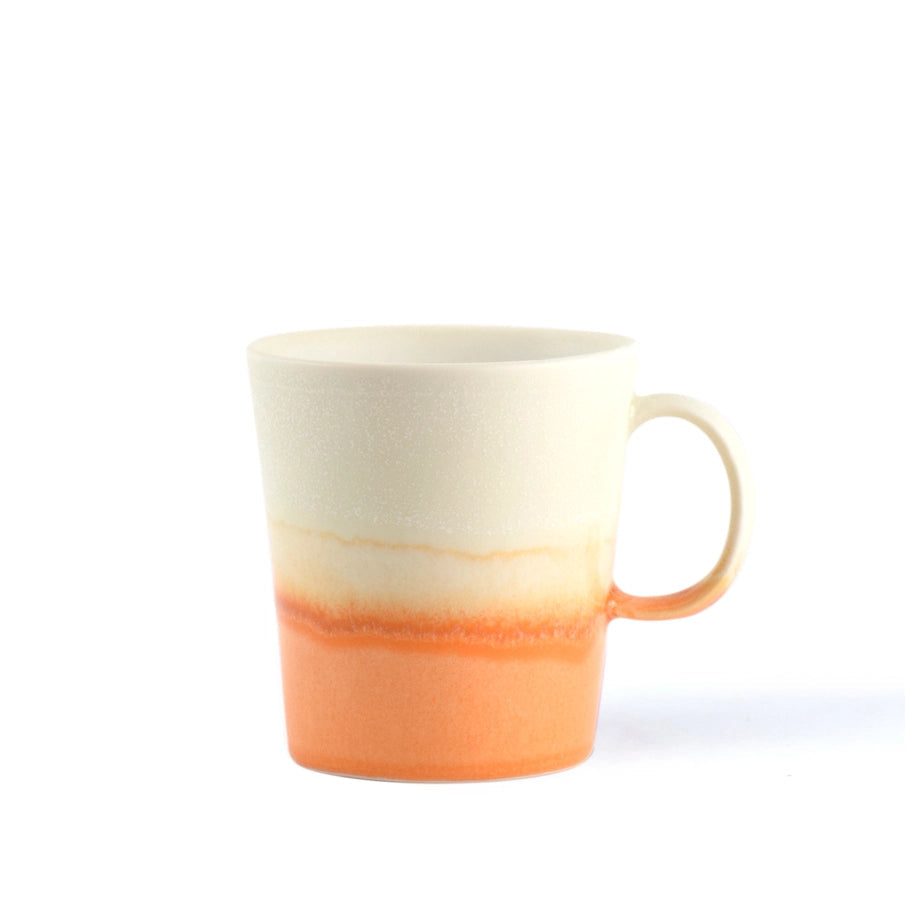 Off-white and orange ombre ceramic mug with a handle.