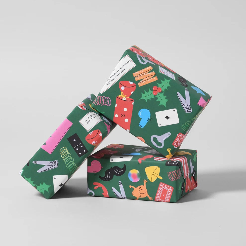 Three gift boxes wrapped in dark green wrapping paper with a colorful Christmas-themed illustration pattern, arranged in a stacked, leaning display on a light gray background.