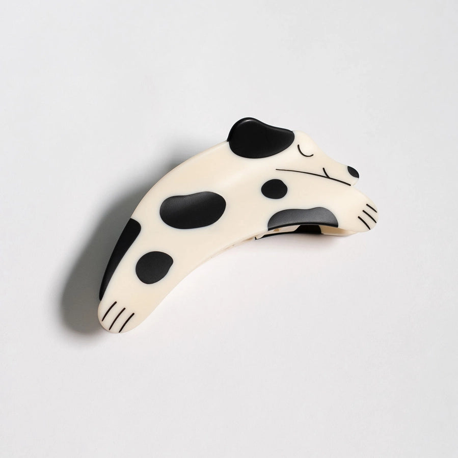A dog shaped hair clip with a dalmatian pattern on a light gray background