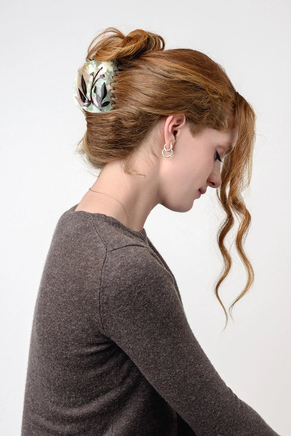 Woman with styled hair wearing a decorative hair accessory against a white background