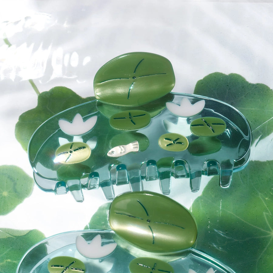 Clear plastic hair clip with green leaf-shaped cavities on a white background